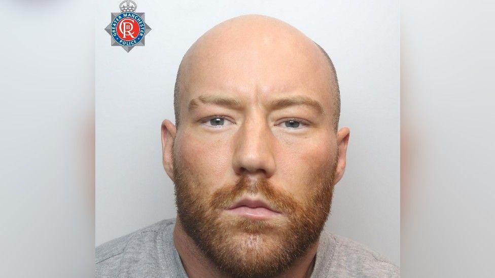 The mugshot of Zach Porter, who is bald and has a ginger-brown coloured beard and is wearing a grey sweatshirt. 