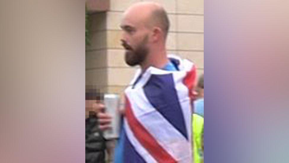 Kieran Usher holding a can and wearing a union jack flag around his shoulders.