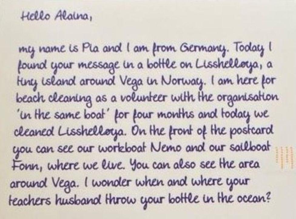 Letter which says: "My name is Pia and I am from Germany. Today I found your message in a bottle on Lisshelløya, a tiny island around Vega in Norway. I am here for beach cleaning as a volunteer with the organisation 'In the same boat' for four months and today we cleaned Lisshelløya. On the front of the postcard you can see our workboat Nemo and our sailboat Fonn, where we live. You can also see the area around Vega. I wonder when and where your teacher's husband threw your bottle in the ocean?"