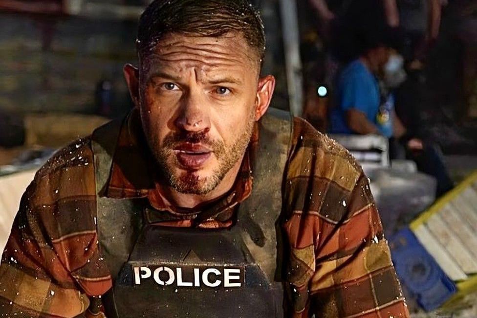 Tom Hardy in character wearing a bulletproof vest marked Police from the film Havoc