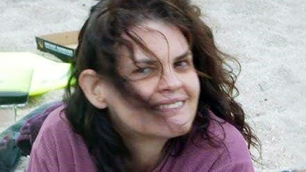 Una Brandreth head an shoulders shot wearing pink top with brown hair blowing in wind on a beach