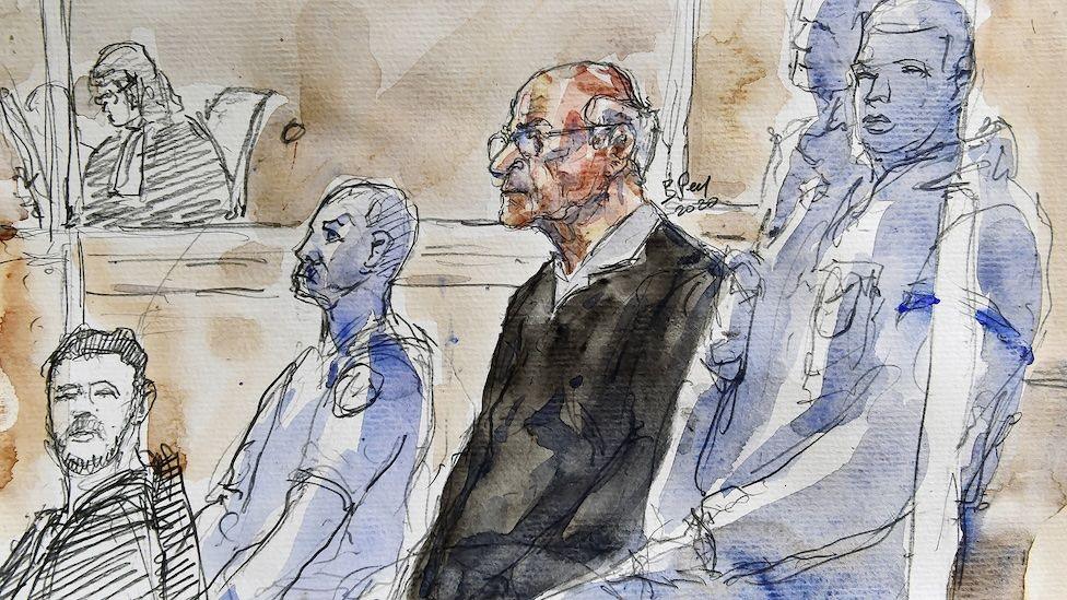 Court sketch shows Joel Le Scouarnec attending his trial for the rape and sexual abuse of four children at the courthouse in Saintes, western France in 2020. Le Scouarnec is dressed in a dark suit. He wears spectacles and is balding with white hair on the back of his head. 