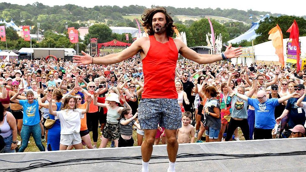 Joe Wicks on a stage in front of people exercising at Glastonbury