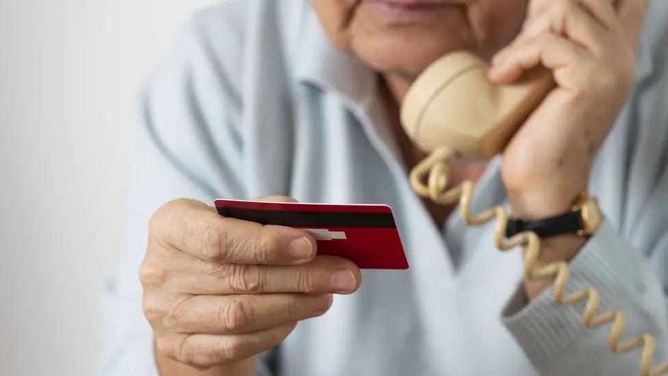 A man on a phone reading bank card details