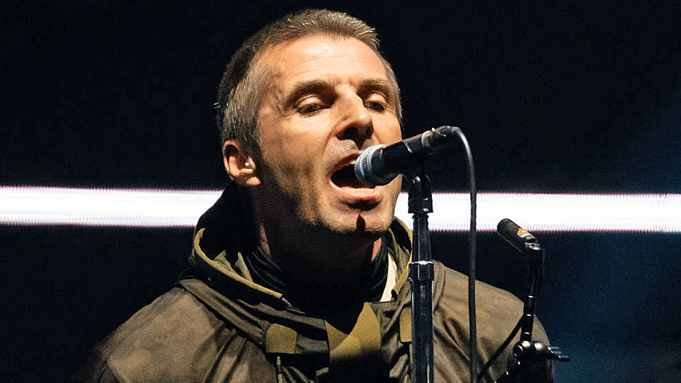 Liam in typical stage stance: Facing forward, chin up, mouth millimetres from the mic, arms behind his back