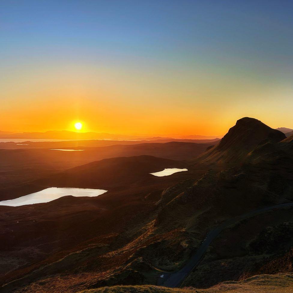 Orange sunrise glow over hilltops in Skye.