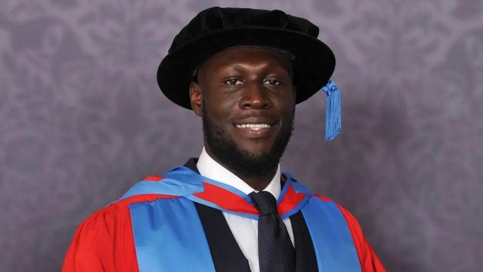 stormy wearing a university cap and gown in blue and red.