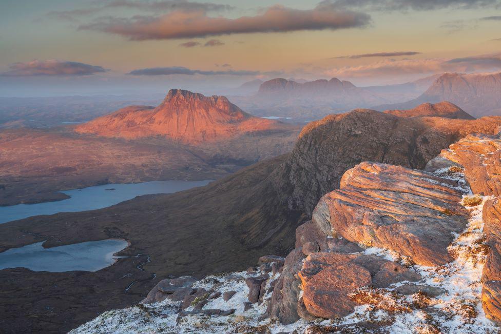 Red tinged sunlight over a rocky and mountainous landscape.