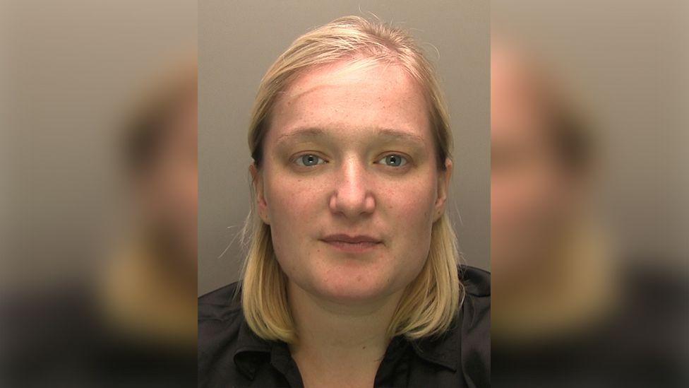 Police custody photograph of Melissa Abolina with shoulder-length blond hair wearing a black shirt