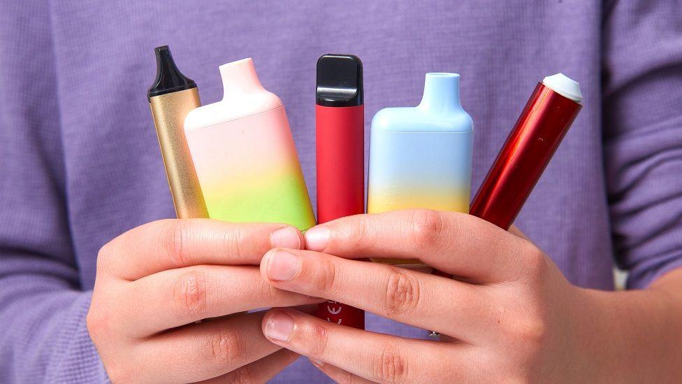 Child holding colourful vapes