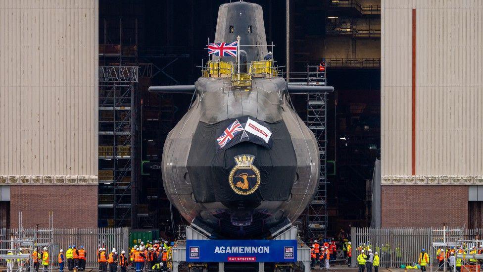 A front shot of HMS Agamemnon at BAE Systems before it was officially launched. About 30 BAE workers surround the submarine outside the hanger in Barrow.