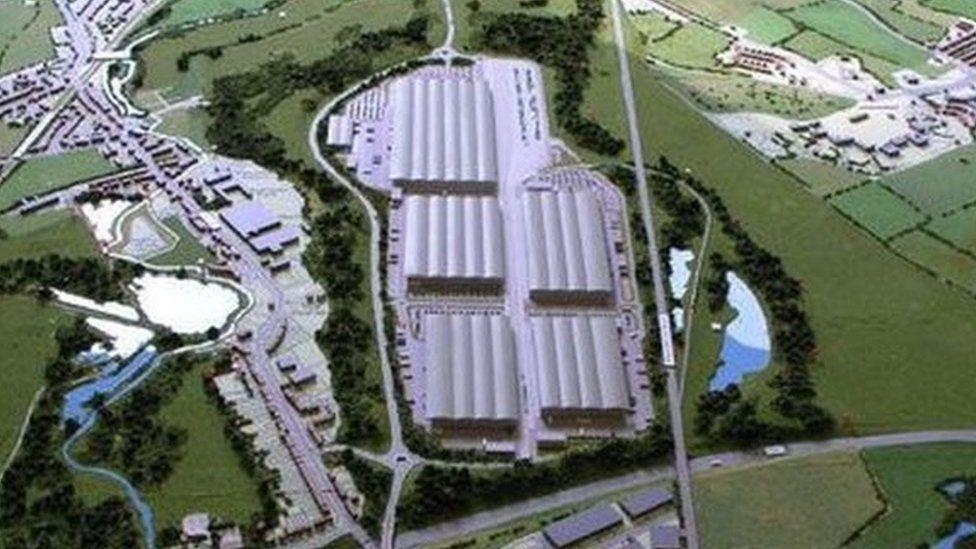 Artist's impression of an aerial shot of the site, showing five blocks of warehouses with undulating roofs, with a small lake to the right.  A development of small industrial units is visible to the left, separated from the warehouses by a line of trees.