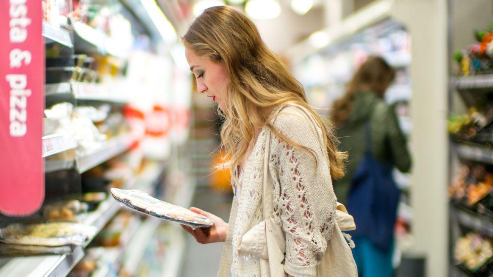 A woman looking at food items in a supermarket