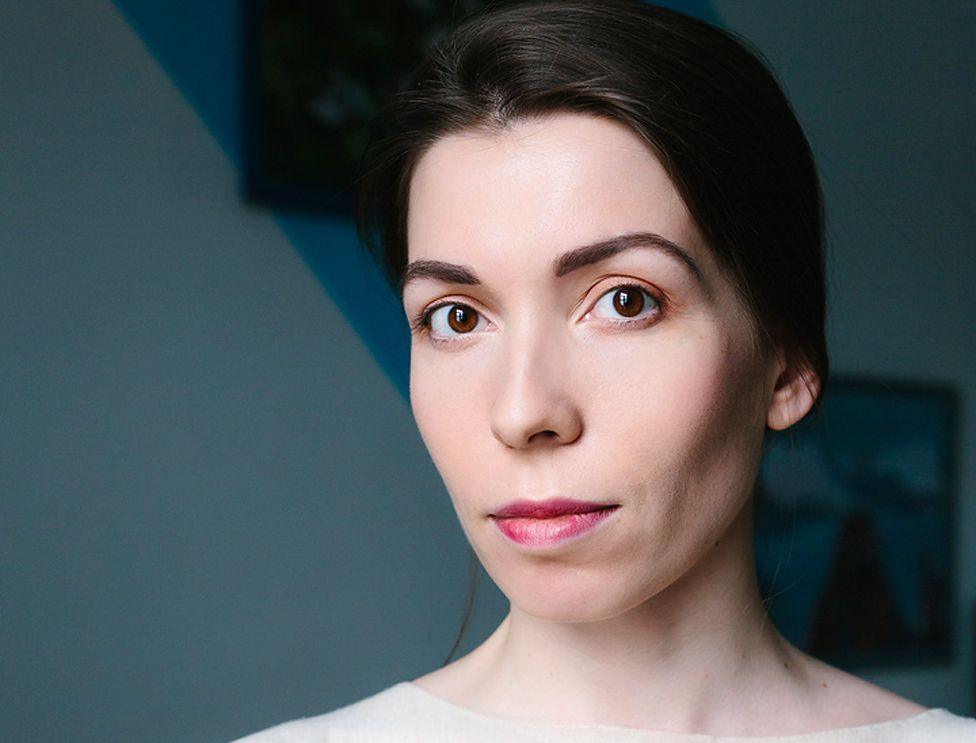 A headshot of Alina Perlova looking at the camera, with her long dark hair tied back.