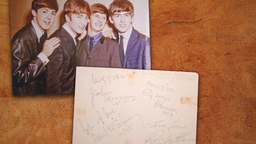 Photographs of the four Beatles with card featuring their signatures