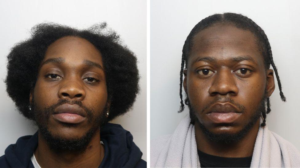 Tyrike has longer dark hair and wears a silver stud in each ear. Jesse has his hair in small braids, and wears what appears to be a white towel around his shoulders.
