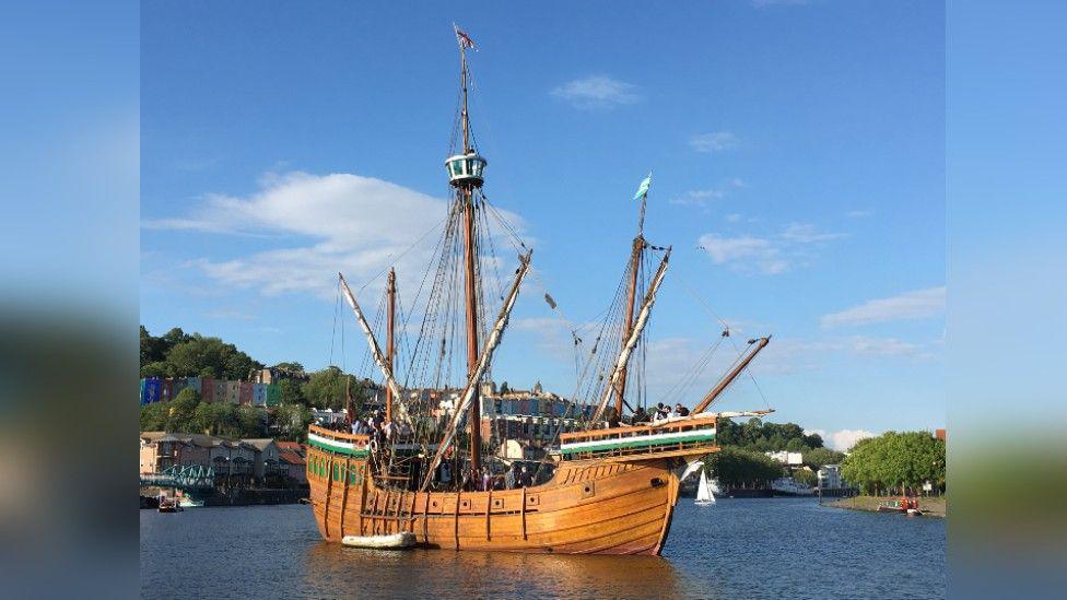 The Matthew sailing in Bristol Harbour on a bright day. You can just about see a line of colourful houses in the background.