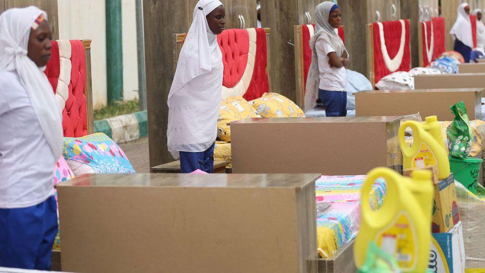 Household items given to couples are seen beside brides at the venue of a wedding reception at the Kano state governor's office after taking part in a mass wedding at the central mosque in Kano city, Nigeria - October 2023