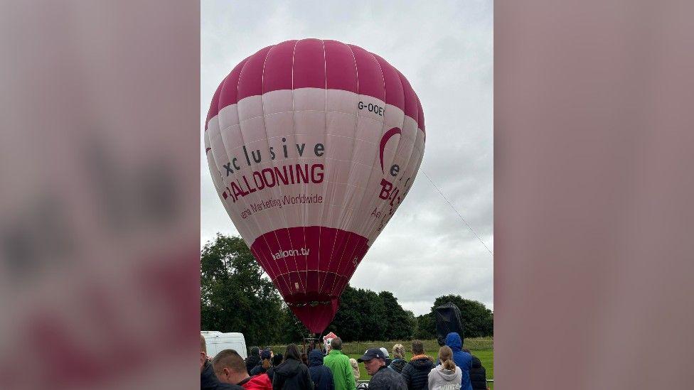 Pink and white hot air balloon on the ground