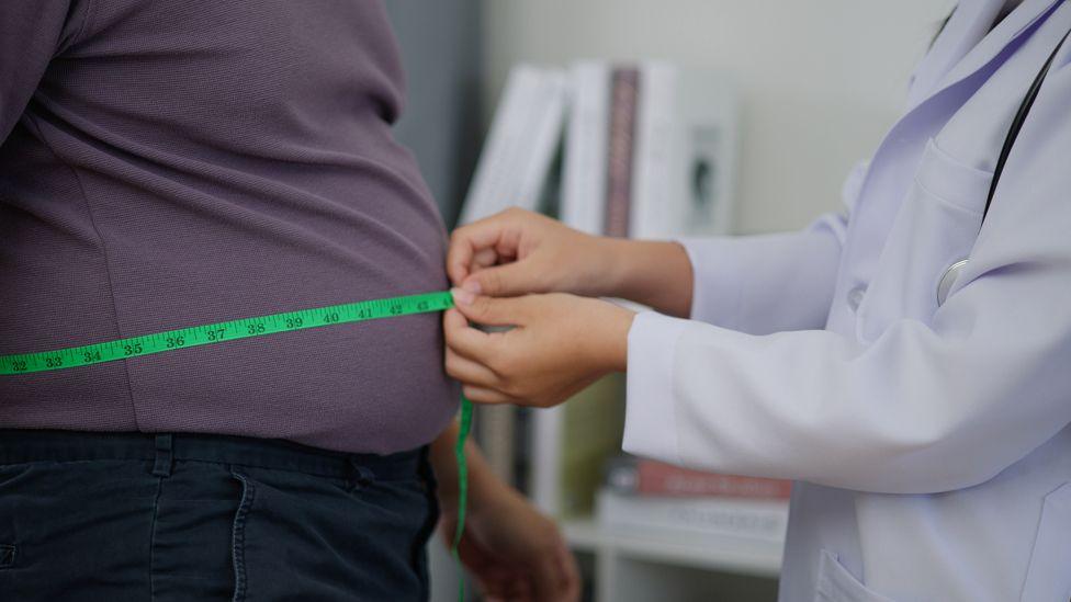 Man having his stomach measured in a health setting 