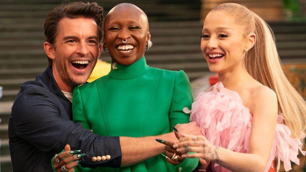 Jonathan Bailey, Cynthia Erivo and Ariana Grande hugging and smiling