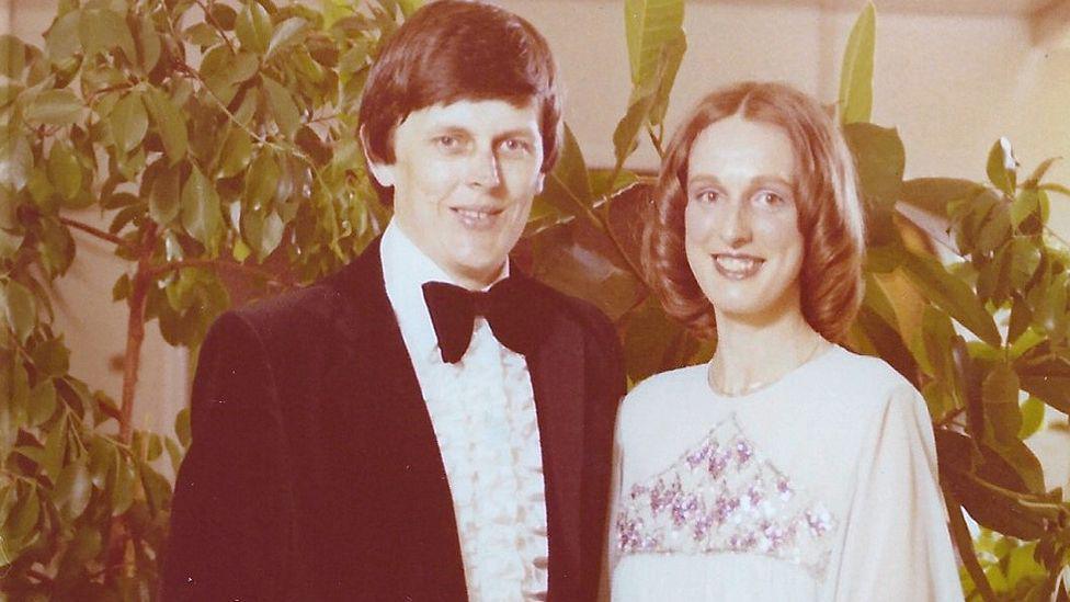 Tony and Jacqueline Butcher Butcher in evening dress with green foliage in the background taken aboard the QE2 in the Caribbean in 1980.