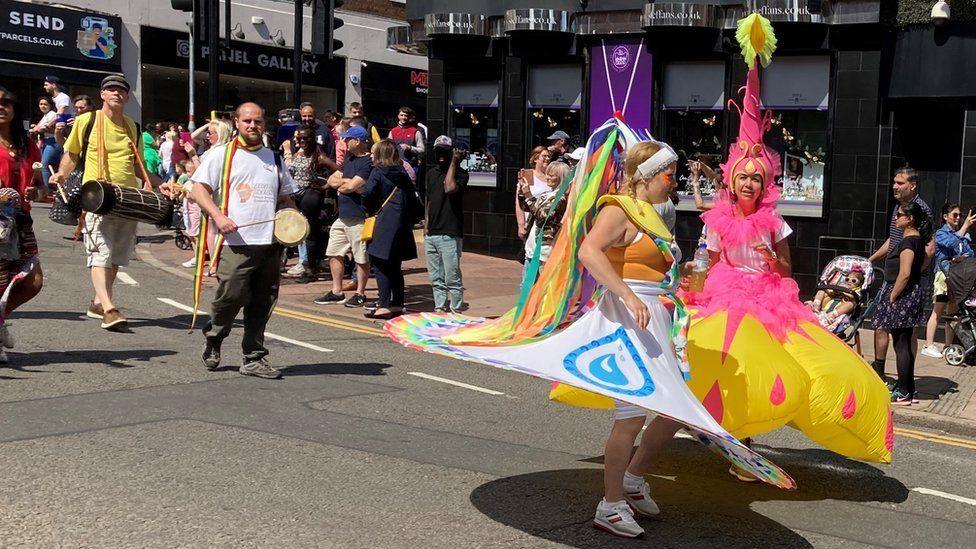 Two women in a parade wearing large inflatable skirts