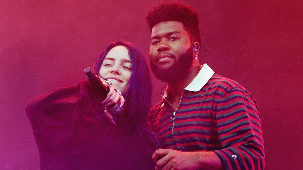 Billie Eilish and Khalid standing together on stage with red smoke