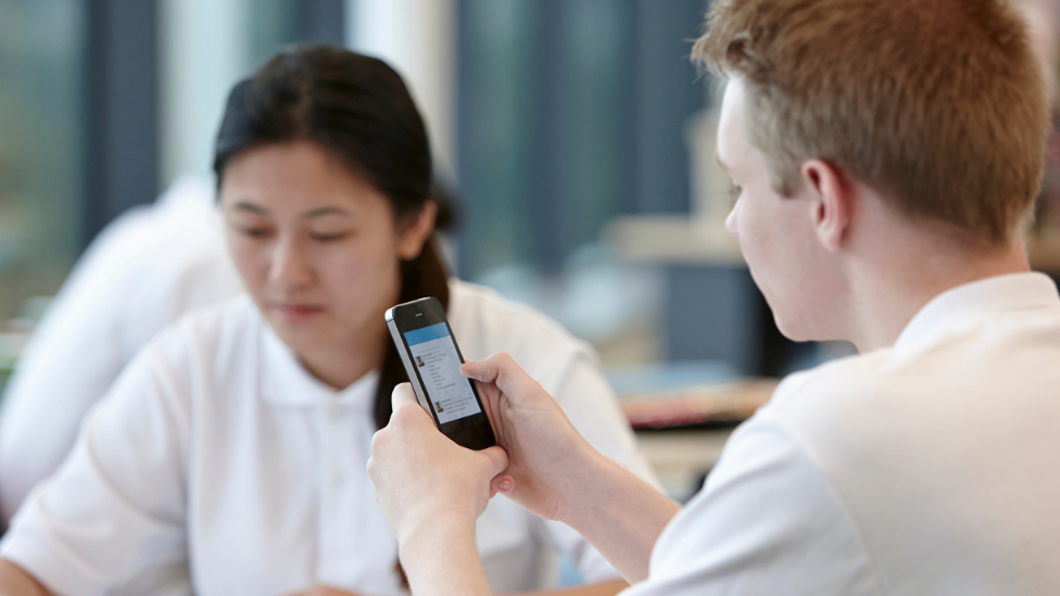 schoolchildren using a smartphone in class