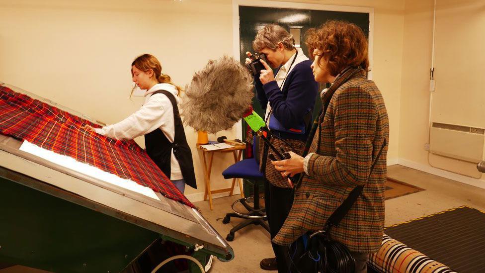 Film makers at work in a Borders textile factory looking at the material made
