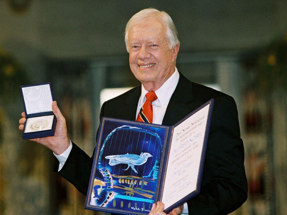 ormer US President Jimmy Carter holds up his Nobel Peace Prize December 10, 2002 in Oslo, Norway. 