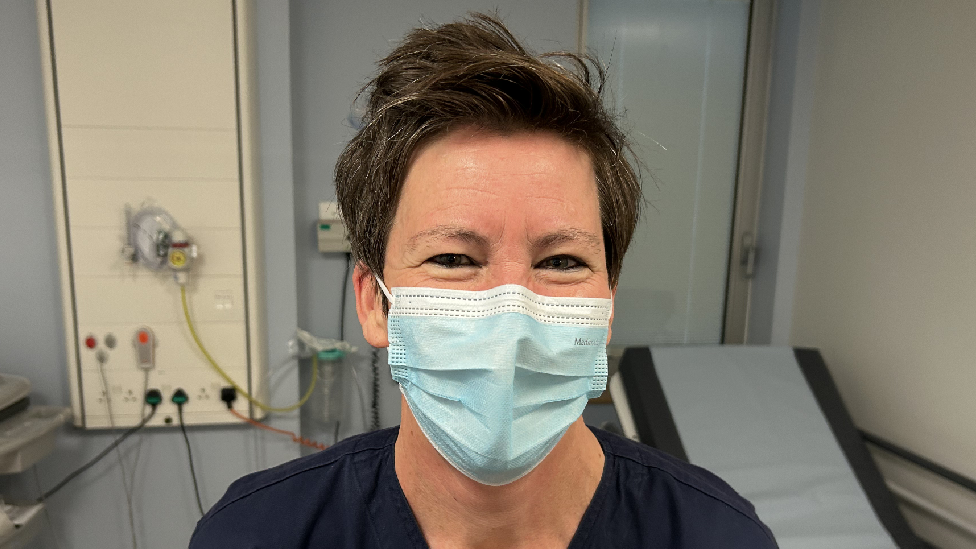 Natasha yn gwenu yn edrych ar y camera. 