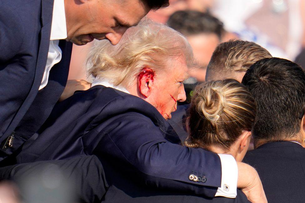 Republican presidential candidate former President Donald Trump is helped off the stage at a campaign event in Butler, Pa., on Saturday, July 13, 2024. 