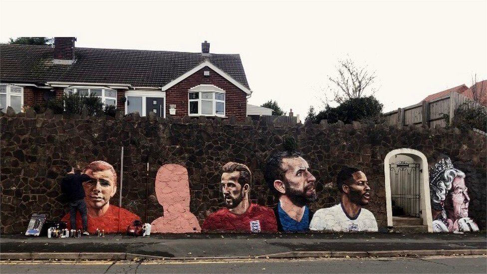 A mural depicting footballers and the Queen