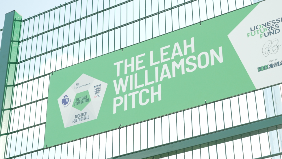 A green sign attached to green railings, which reads: "The Leah Williamson Pitch."