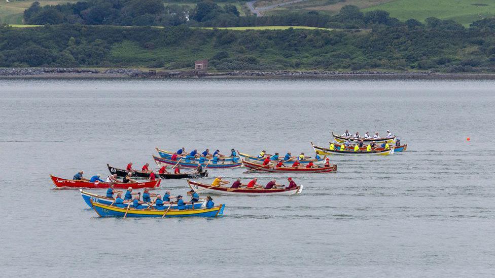 A number of colourful boats race across Loch Ryan in the south of Scotland