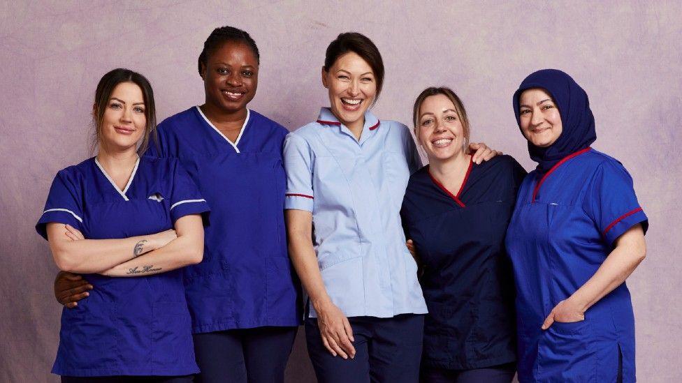 Emma Willis (pictured centre) with four midwives all in blue uniforms