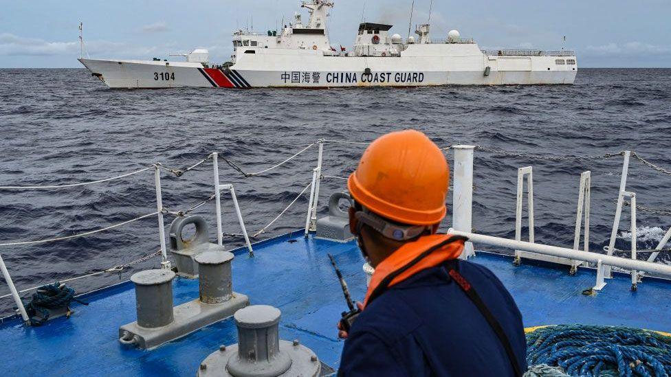 A Philippine coast guard looks at a Chinese coast guard ship