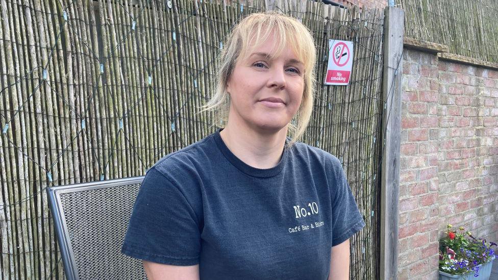 Caroline Lane sitting outside in front of bamboo fence