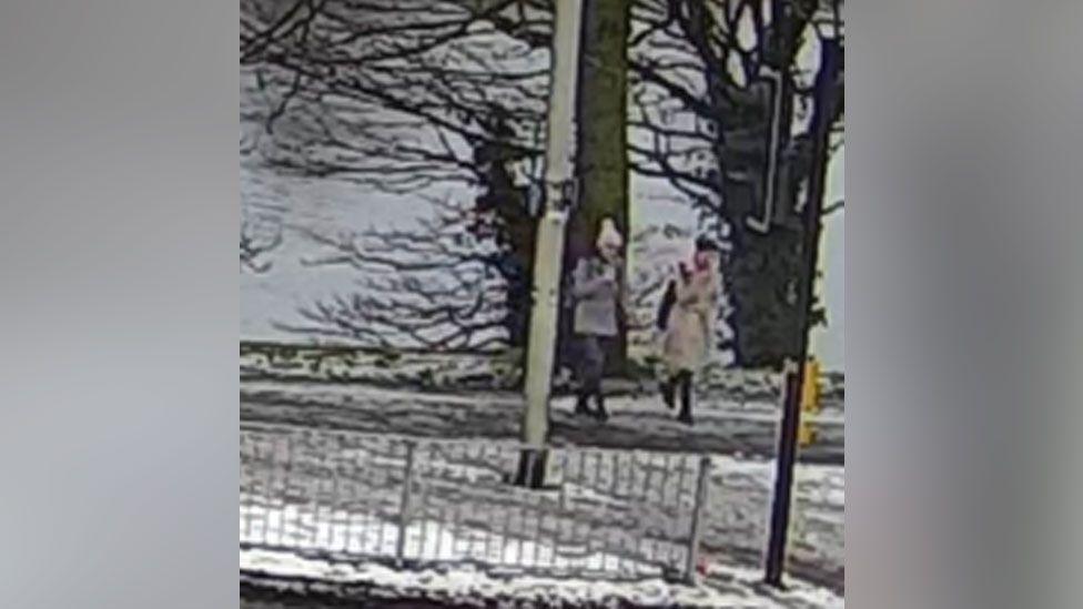 Very grainy CCTV footage of the two sisters in jackets on a bridge