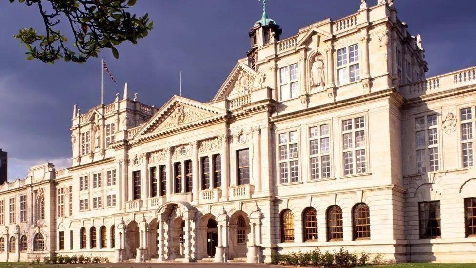 The outside of an old university building. It is made of a light stone and has hundreds of windows and intricate detailing.