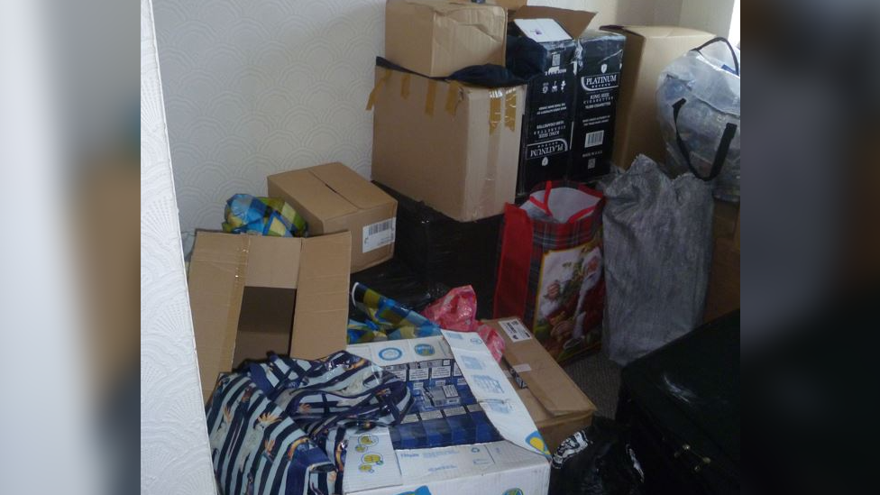 Boxes and bags filed with products piled in a room.