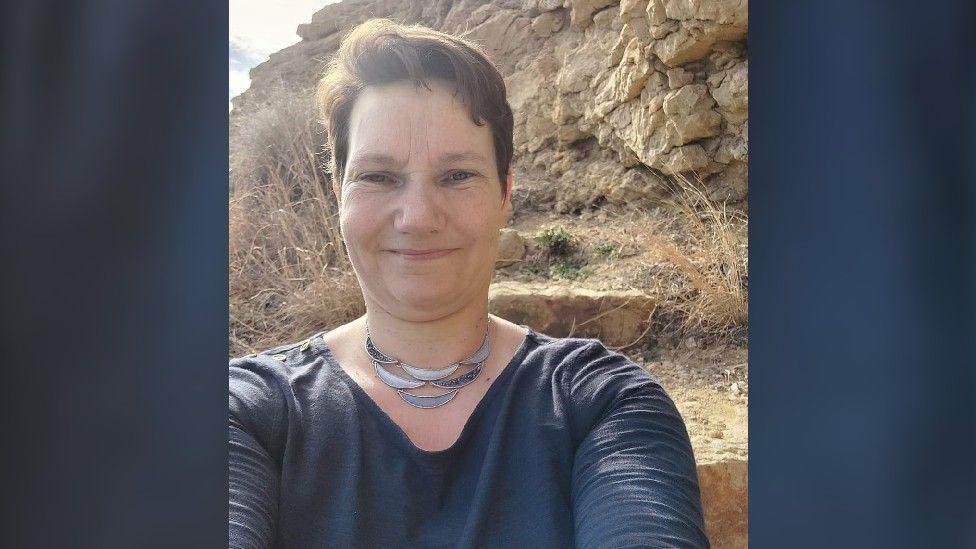 Maire Laing with short brown hair, standing in front of a cliff face