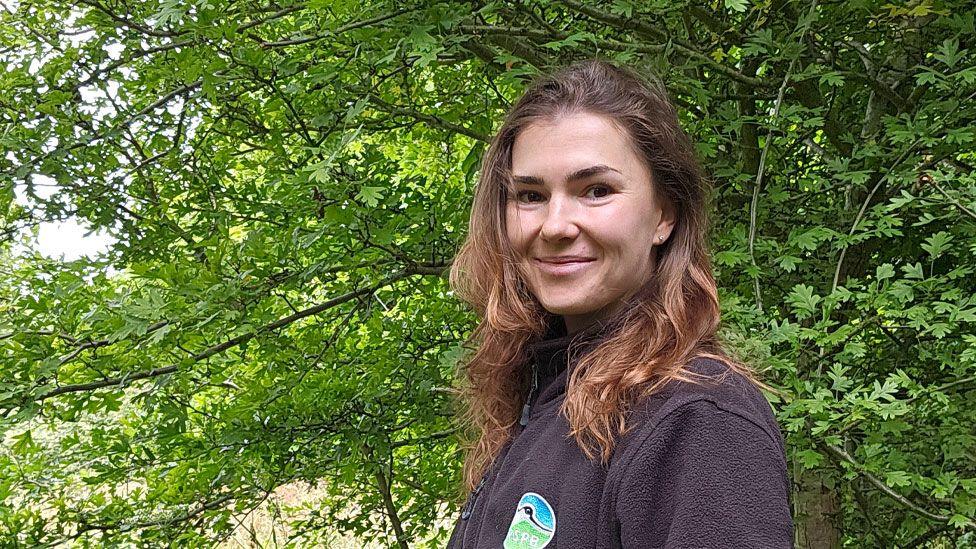 Sophie Arnold turned to look at the camera with a young and very leafy tree behind her