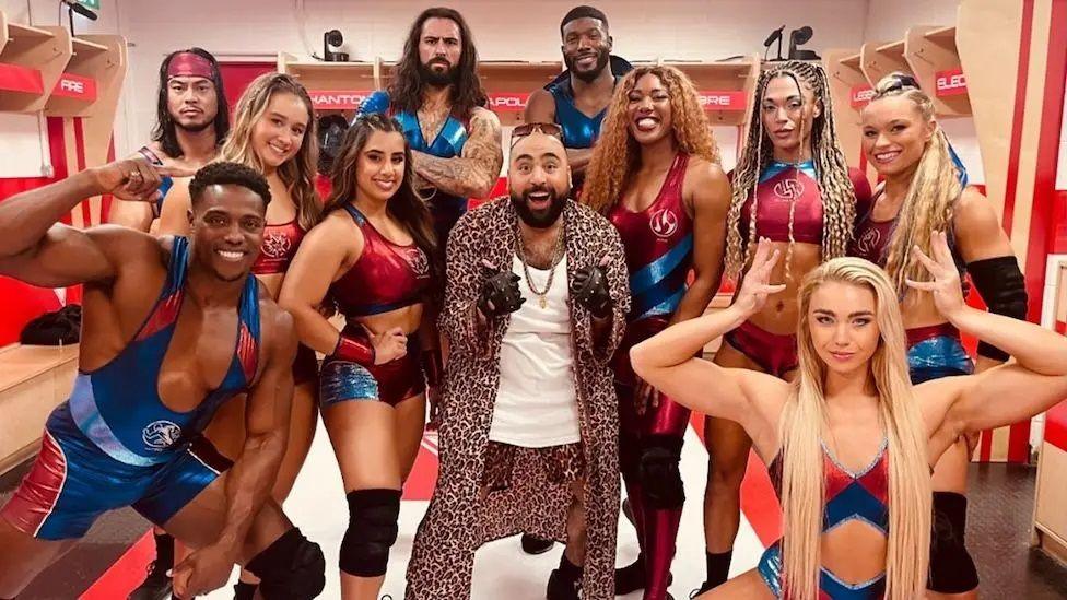 Chabuddy G actor Asim Chaudhry surrounded by the cast of Gladiators
