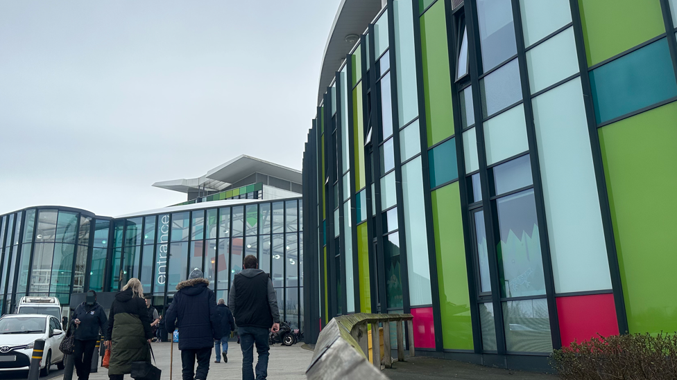 Exterior of King's Mill hospital entrance showing people walking around the colourful glass frontage