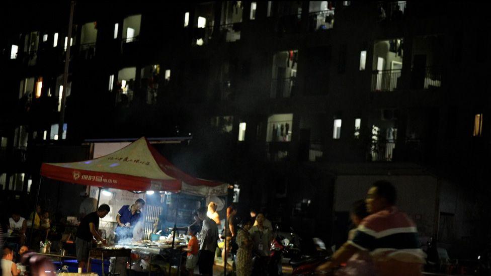 A man sells food in front of a block where workers live 