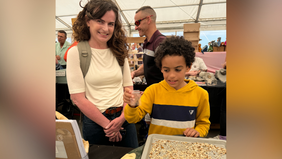 James at the festival with his mum, holding the tooth in a small clear plastic pouch