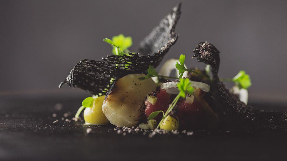 Holstein Friesian, barbecued celeriac, mustard and shallot artfully arranged on a black plate