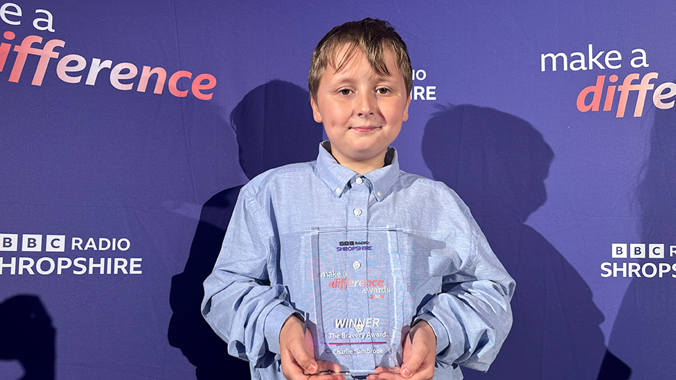 Young cancer survivor Charlie holding his award